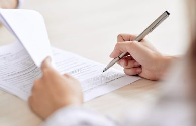 Crop shot of person with pen signing contract at desk in daylight